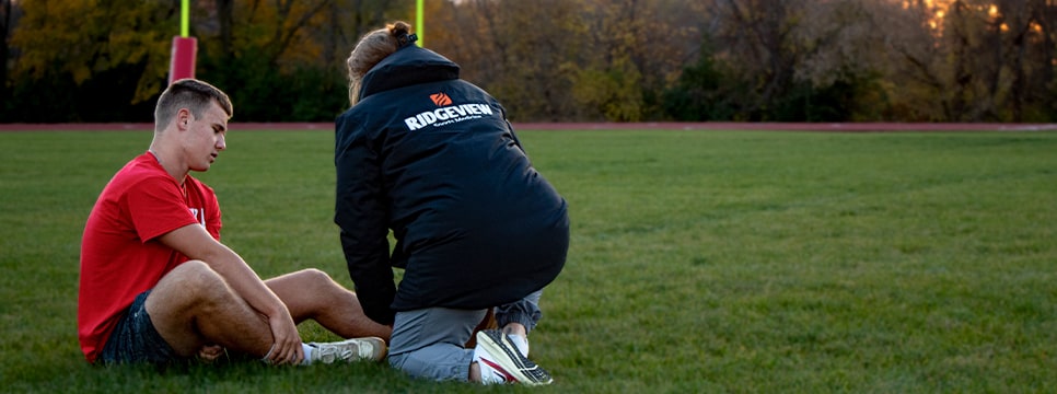 Athletic trainer examining player injury on field