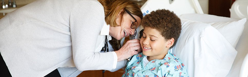 Photo of nurse comforting a pediatric patient in a hospital bed